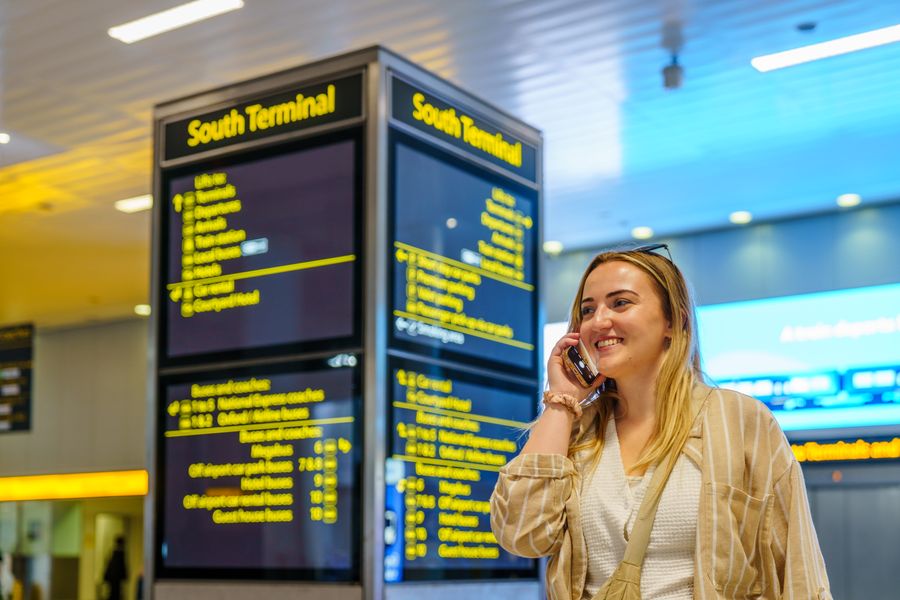 Traveler smiling on the phone at an airport terminal