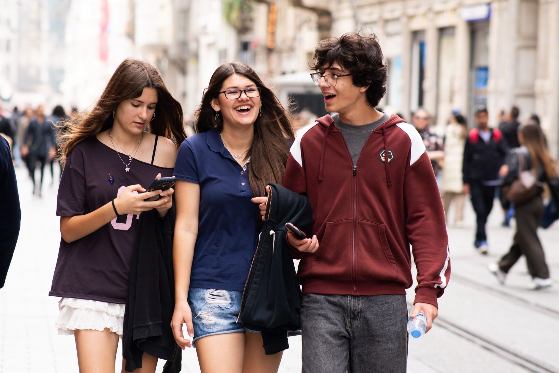 Three friends exploring a city street with their phones