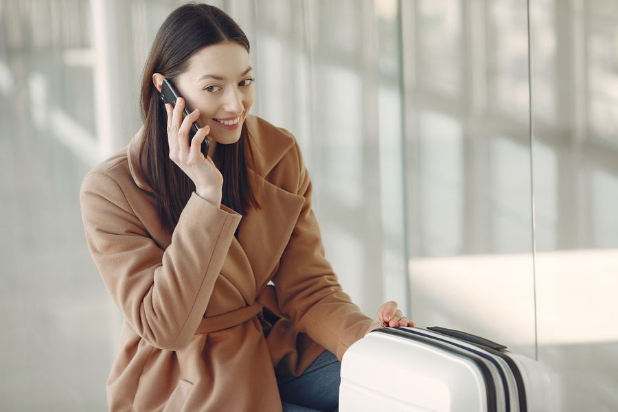 Traveler smiling confidently while on the phone with her suitcase