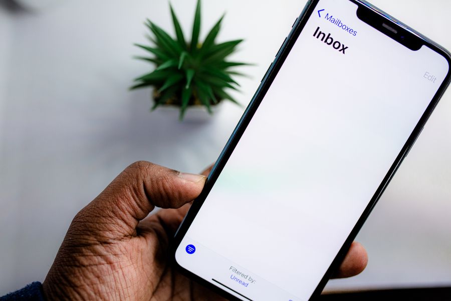 Hand holding a phone showing an inbox, ready to receive the eSIM email